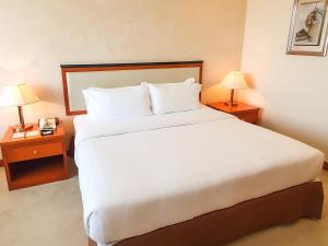 a large bed in a hotel room with two lamps at Parkview Hotel in Kampong Jerudong