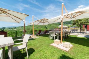 a patio with tables and chairs and umbrellas at Agriturismo Il Follo in Valdobbiadene