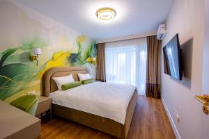 a bedroom with a bed with a painting on the wall at Galant Apartments in Cluj-Napoca