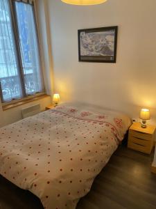 een bed in een slaapkamer met 2 lampen en 2 ramen bij Val-locations thermes 5 in Le Mont-Dore