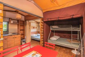 two bunk beds in a room with a table at Camping Onlycamp du lac de Roybon in Roybon