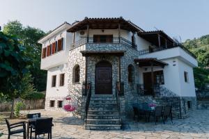 a house with chairs and tables in front of it at Aria Archontiko Pelion in Katochori