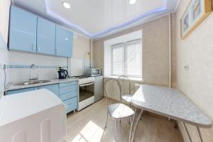 チェリャビンスクにあるInnHome Apartments Plekhanova Street 14のキッチン(青いキャビネット、テーブル、椅子付)