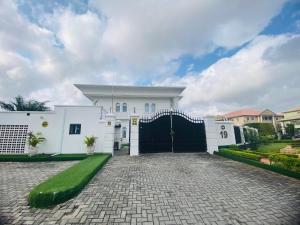 a white house with a black gate and a driveway at Presken Hotel White House, Lekki, Lagos in Lagos