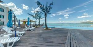 a wooden boardwalk with white chairs and a pool at Marina City ApartHotel in Balchik