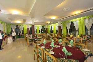 a dining room with green curtains and tables and people at Periyar Meadows Leisure Hotel in Thekkady