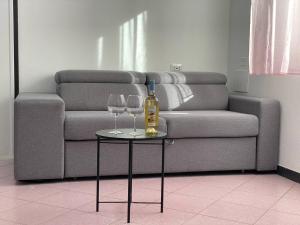 two wine glasses and a bottle on a table in front of a couch at Domus Gianni in Assemini