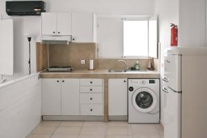 a kitchen with white cabinets and a washing machine at Santorini's Old Mill Serene Getaway by Pori Beach in Vourvoulos