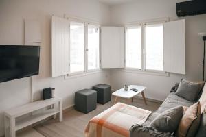 a living room with a couch and a tv at Santorini's Old Mill Serene Getaway by Pori Beach in Vourvoulos