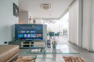 a living room with a tv and a glass table at Fin Villa Bang Saray in Bang Sare