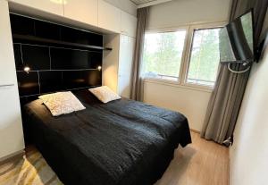 een slaapkamer met een groot zwart bed met 2 kussens bij Vuokatti Weekend Piste in Vuokatti