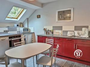 eine Küche mit roten Schränken sowie einem Tisch und Stühlen in der Unterkunft NORMANDIE in Lassay