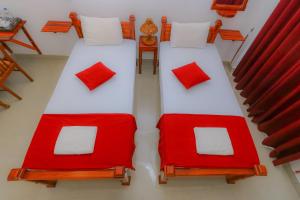 two beds with red and white pillows in a room at Castle Resort Yala in Tissamaharama