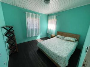 a bedroom with blue walls and a bed and a window at Villa Emma Ampefy in Ambatoasana Afovoany