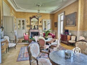 a living room with chairs and tables and a fireplace at Château de la Roche, 11-12 personnes in Ahuillé