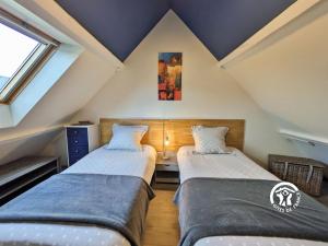 a attic room with two beds and a window at Le Pêcheur d'étoiles in Origné