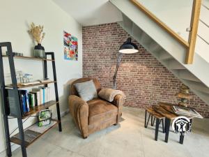 a living room with a chair and a book shelf at Le Pêcheur d'étoiles in Origné