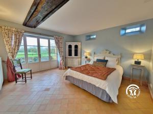 a bedroom with a large bed in a room with windows at Le Moulin Renaud, 8 personnes 