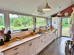 a large kitchen with white cabinets and a large window at Le Moulin Renaud, 8 personnes 