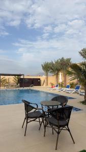 拉斯阿尔卡麦sea breeze RAK的游泳池旁的一张桌子和两把椅子