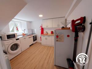 a kitchen with a washing machine and a refrigerator at La Douce Escapade in Andouillé