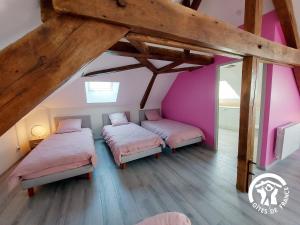 2 letti in una camera con pareti rosa e pavimenti in legno di Les Grands Blés d'Or, 12 personnes a Saint-Aubin-du-Désert