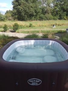 une baignoire jacuzzi au milieu d'un champ dans l'établissement La Lande du Pont, à Hambers