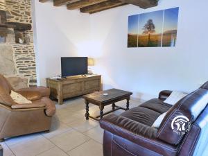 a living room with a leather couch and a tv at Les gallinettes in Neuilly-le-Vendin