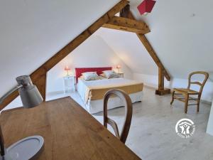 a attic bedroom with a bed and a table at Les gallinettes in Neuilly-le-Vendin +30 photos