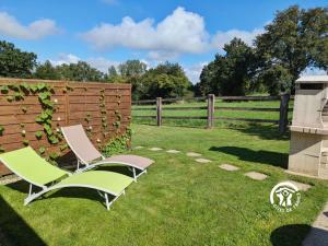 twee stoelen in een tuin naast een hek bij Les gallinettes in Neuilly-le-Vendin