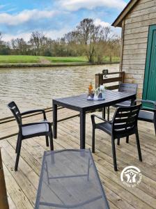 a picnic table and chairs on a dock next to a river at Chalet la Tanche in Villiers-Charlemagne