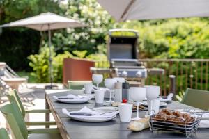 a table with plates and glasses and a grill at La Loge aux Loups, à 100 m du lac, piscine intérieure, sauna, cheminée, local skis vélos in Gérardmer