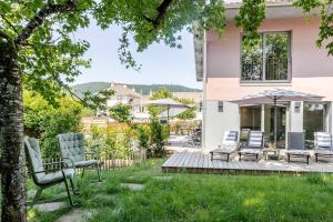 a yard with two chairs and an umbrella at La Loge aux Loups, à 100 m du lac, piscine intérieure, sauna, cheminée, local skis vélos in Gérardmer
