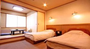 a room with two beds and a table and a window at Oga Onsenkyo Oga Hotel in Oga