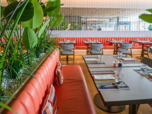 a restaurant with tables and chairs and plants at Falkensteiner Residences Jesolo in Lido di Jesolo +26 photos
