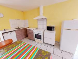 a kitchen with yellow walls and a white refrigerator at La Boulaie in Saint-Ouen-des-Toits