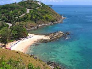 a beach with a group of people in the water at Baan Bua Nai Harn 3 bedrooms Villa in Nai Harn Beach