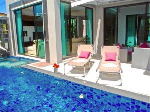 two chairs sitting next to a swimming pool at Baan Bua Nai Harn 3 bedrooms Villa in Nai Harn Beach