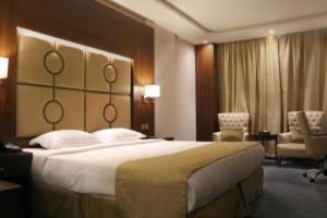una camera d'albergo con un grande letto e due sedie di Sunday Harbour Gateway Jeddah Beach Formerly Vivid Plaza Hotel a Gedda