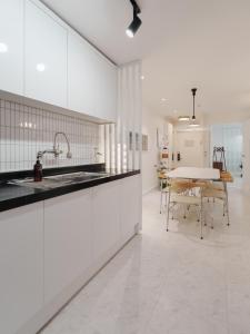 Una cocina con gabinetes blancos y una mesa con sillas. en Kefi, en Seúl