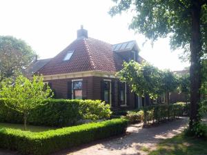uma casa com um telhado vermelho e alguns arbustos em Vakantie appartement in dorpskern em Diever