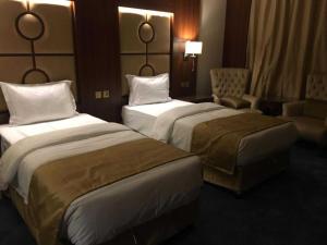 una stanza d'albergo con due letti e una sedia di Sunday Harbour Gateway Jeddah Beach Formerly Vivid Plaza Hotel a Gedda