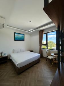 a bedroom with a bed and a desk and a window at Hilaria Hotel in Vạn Ninh