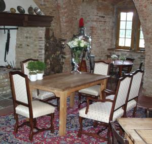 una mesa de comedor con sillas y un jarrón de flores en Burg Boetzelaer, en Kalkar