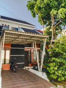 a house with a motorcycle parked under a wooden pergola at Terrace Hills Villa Malang in Karangploso