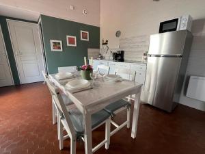 a kitchen with a white table and a refrigerator at Cottage les Écuries du faubourg in Béthune +7 photos