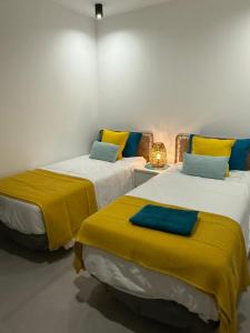 two beds with yellow and blue pillows in a room at Stylish and comfortable Villa Anna in Villaverde in Lajares +37 photos