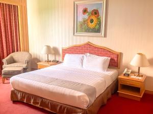 a hotel room with a bed and a chair at Parkview Hotel in Kampong Jerudong