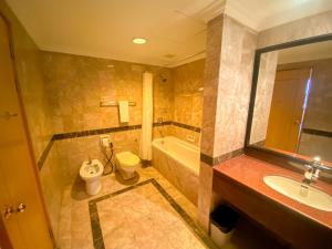 a bathroom with a tub and a toilet and a sink at Parkview Hotel in Kampong Jerudong