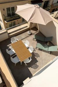 a wooden table and chairs and an umbrella on a balcony at The Penthouse by Shmoo - Sliema Ferries in Sliema